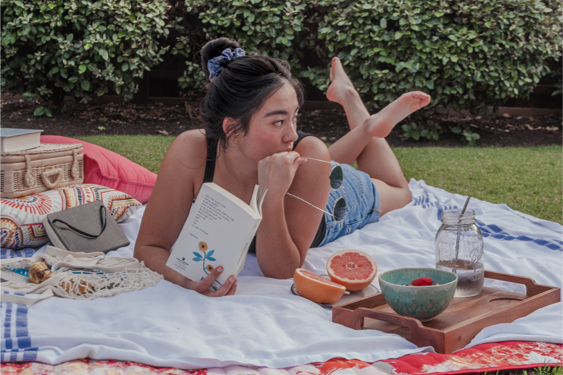 girl reading a book while having a picnic