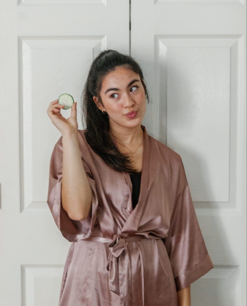 Girl in a robe with holding a cucumber slice