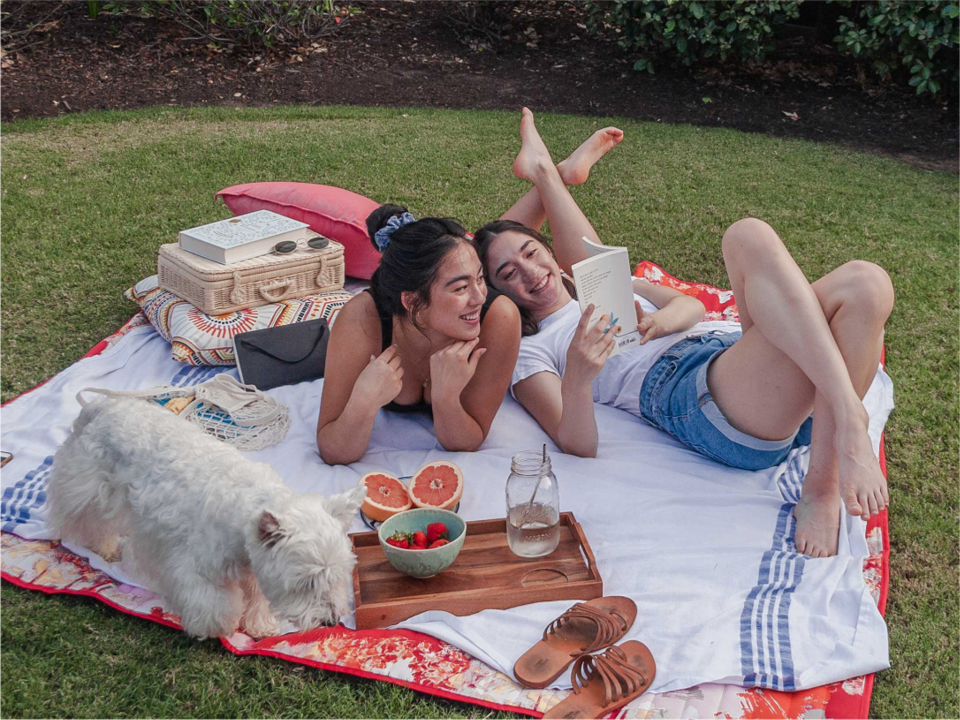 two girls laying on a picnic blanket